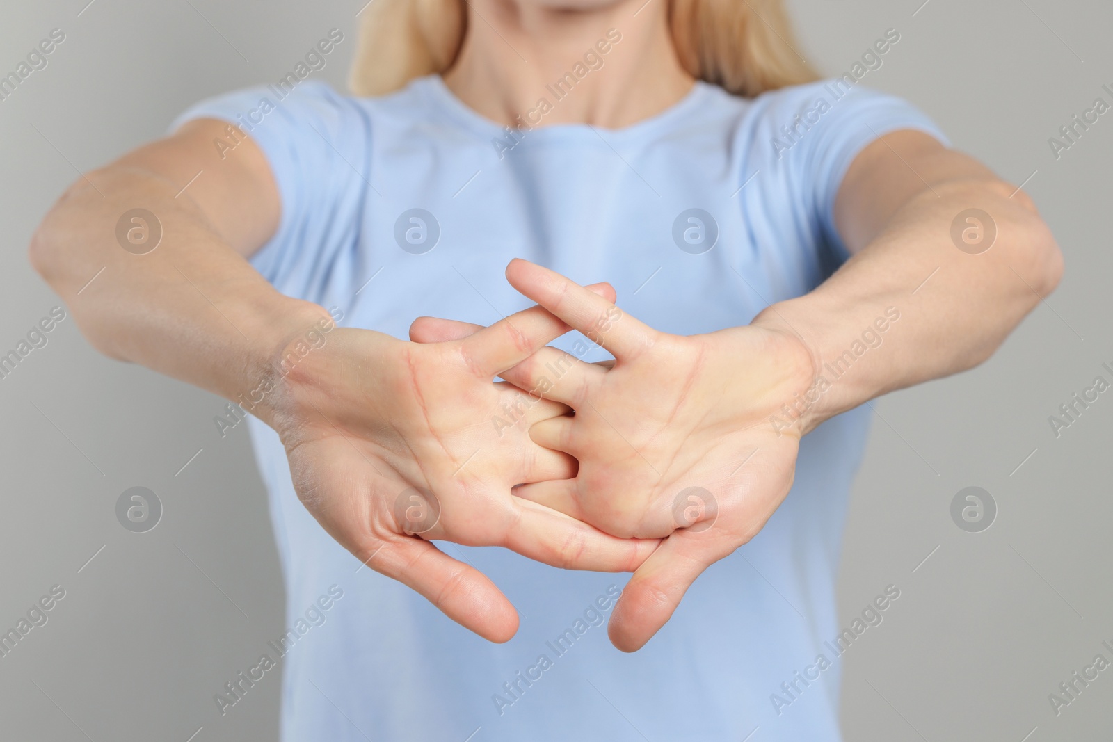 Photo of Woman cracking her knuckles on light grey background, closeup. Bad habit