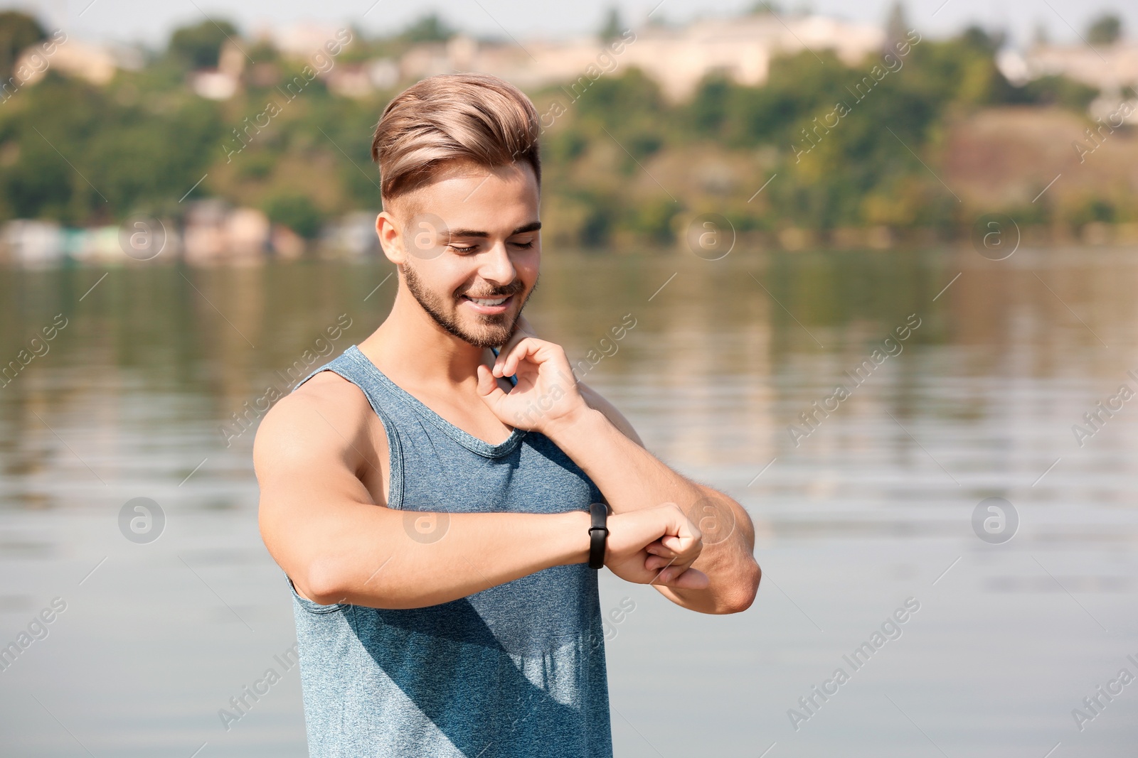 Photo of Young man checking pulse outdoors on sunny day