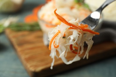 Fork with fermented cabbage on blurred background, closeup