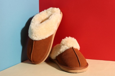 Pair of soft slippers on color background