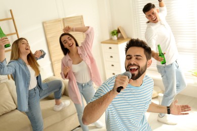 Young man singing karaoke with friends at home