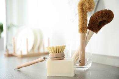 Photo of Cleaning brush and soap bar for dish washing on wooden table