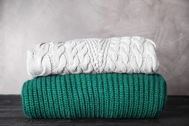 Folded warm sweaters on black wooden table 