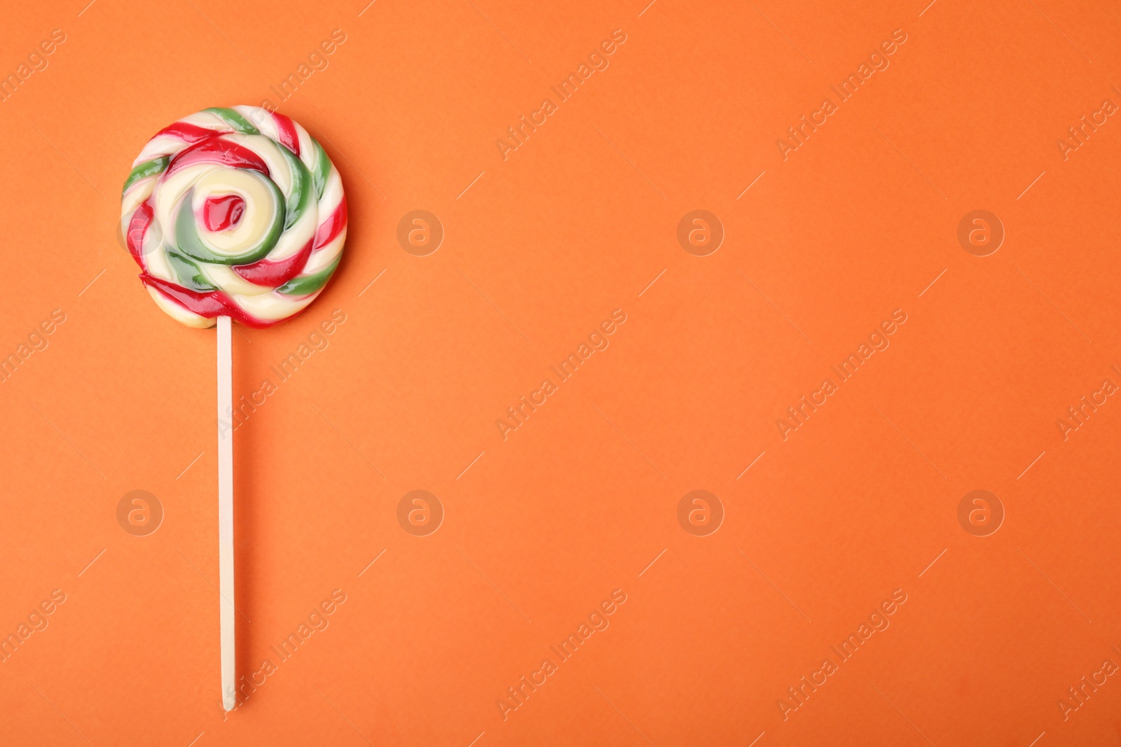 Photo of Colorful lollipop on orange background, top view. Space for text