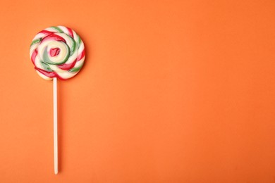 Colorful lollipop on orange background, top view. Space for text