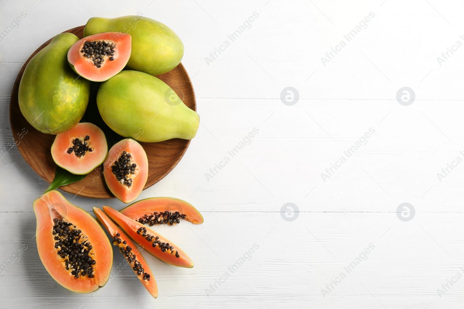 Photo of Fresh ripe papaya fruits on white wooden table, flat lay. Space for text