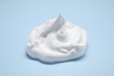 Photo of Sample of shaving foam on light blue background, closeup