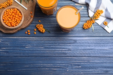 Photo of Flat lay composition with sea buckthorn juice on blue wooden table, space for text