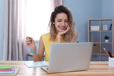 Photo of Young woman working with laptop at desk. Home office