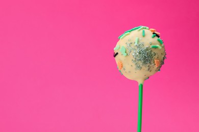 Delicious confectionery. Sweet cake pop decorated with sprinkles on pink background, closeup. Space for text