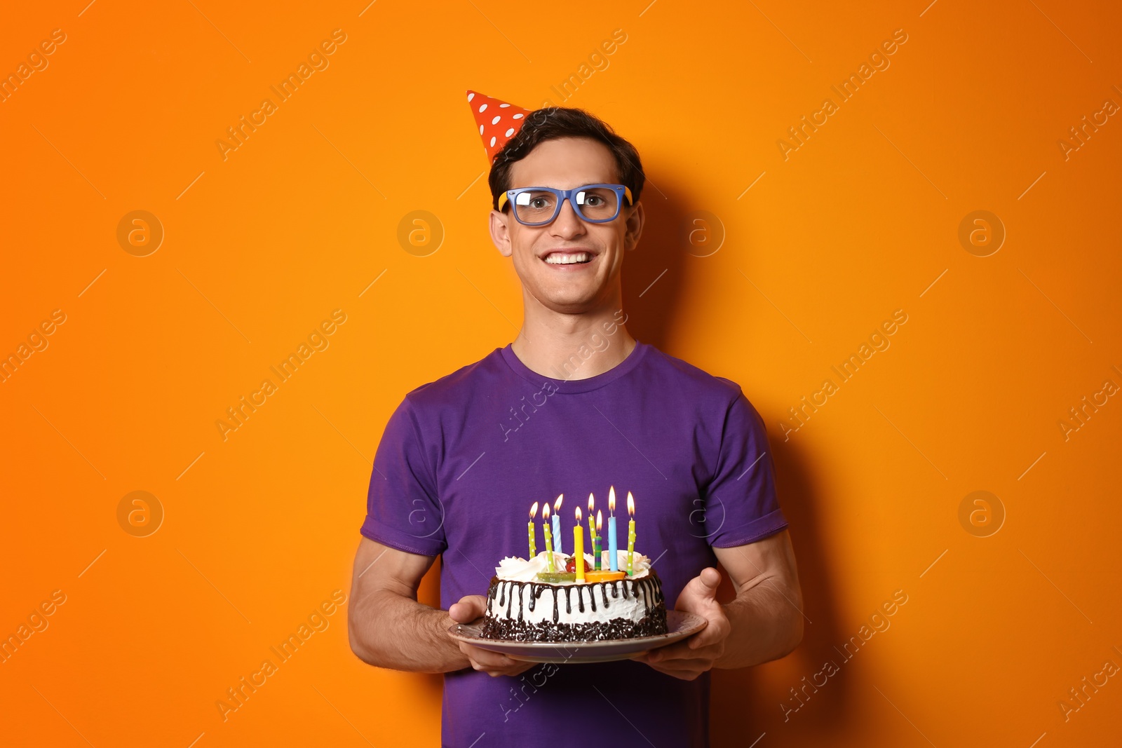 Photo of Young man with birthday cake on color background