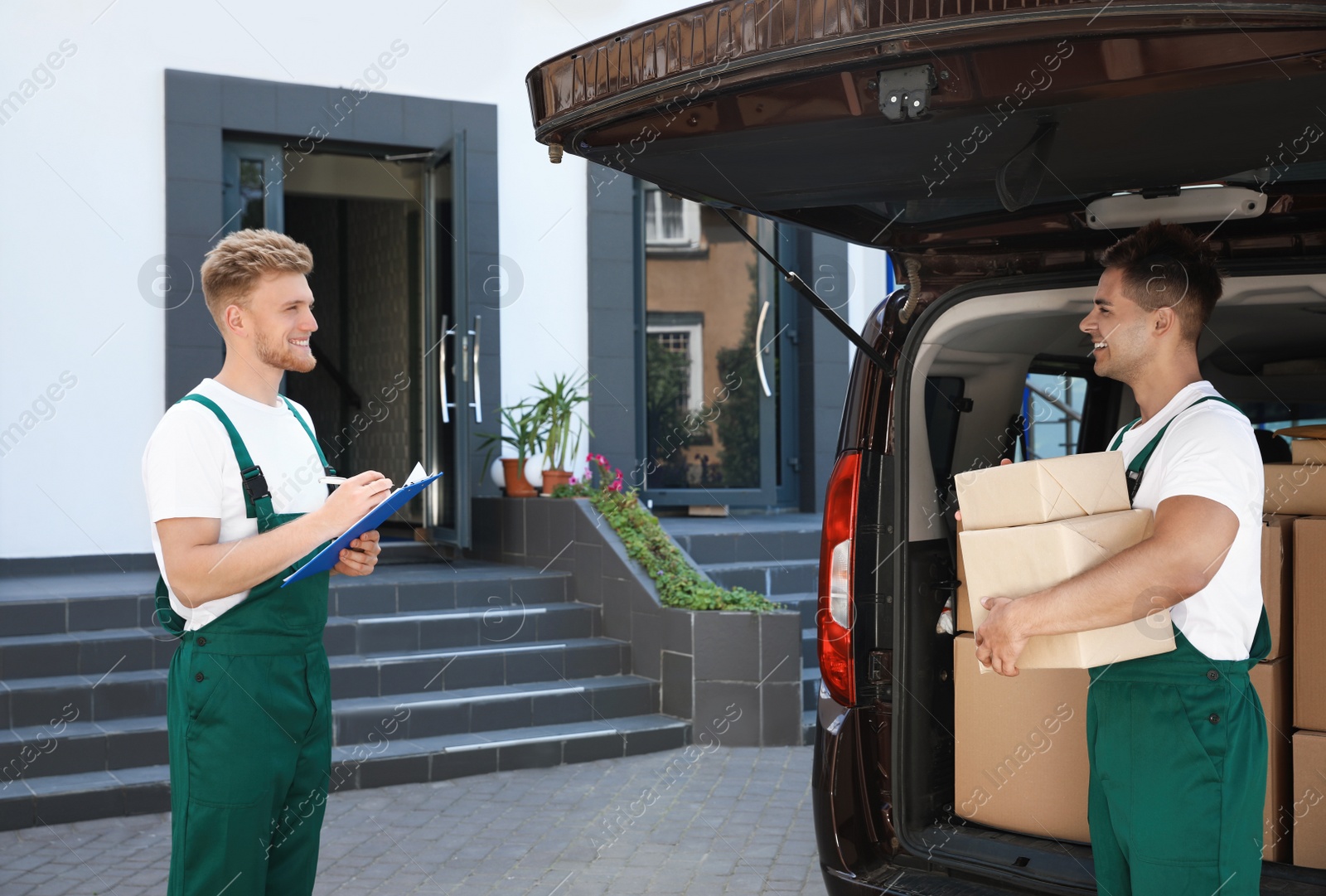 Photo of Young couriers with parcels near delivery car outdoors