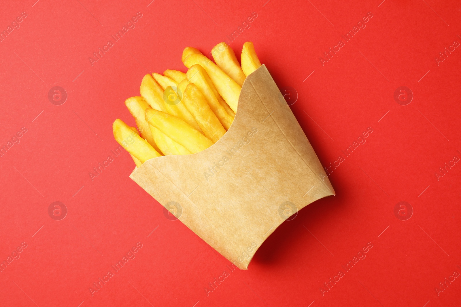 Photo of Paper cup with French fries on red table, top view