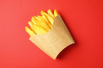 Paper cup with French fries on red table, top view