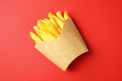 Photo of Paper cup with French fries on red table, top view