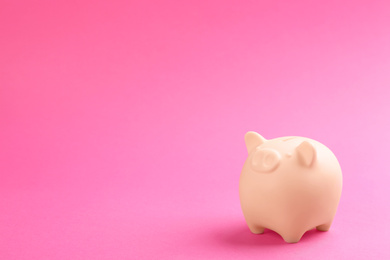 Photo of Beige piggy bank on pink background. Space for text