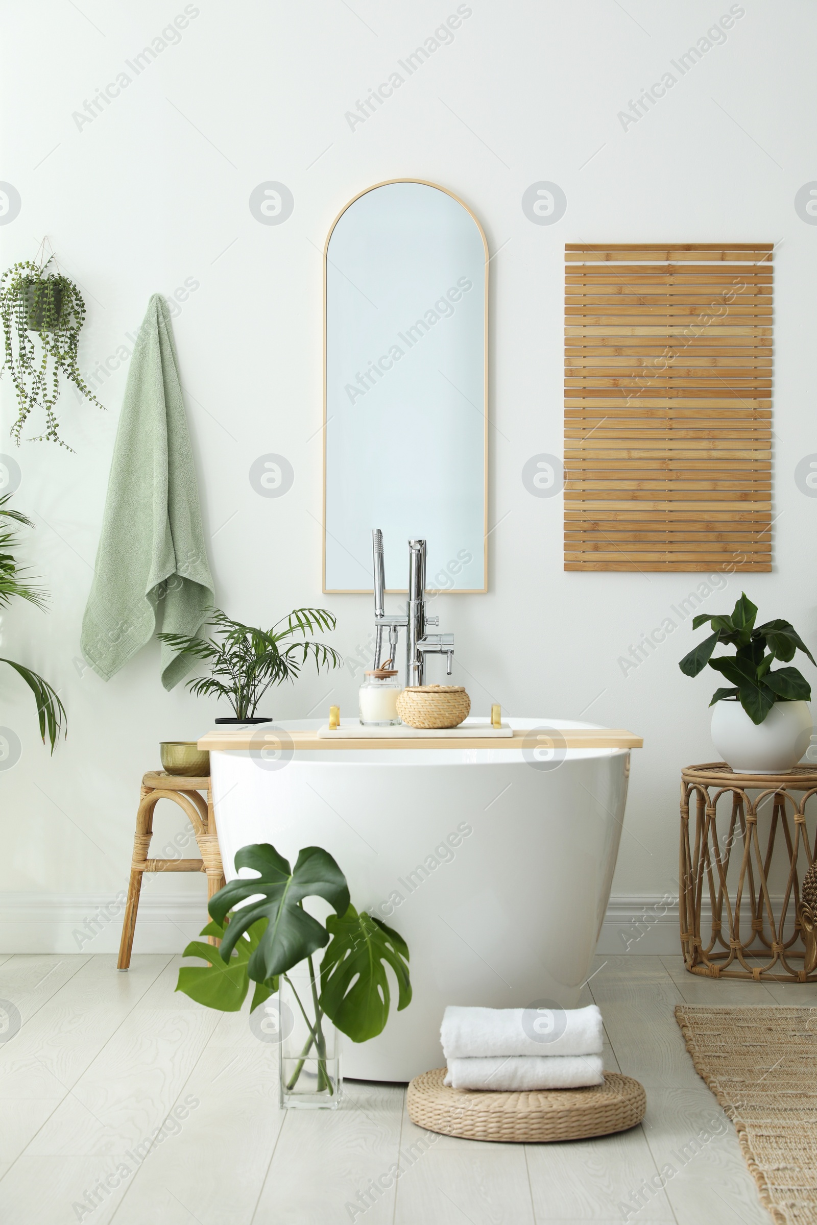 Photo of Stylish bathroom interior with modern tub, houseplants and beautiful decor. Home design