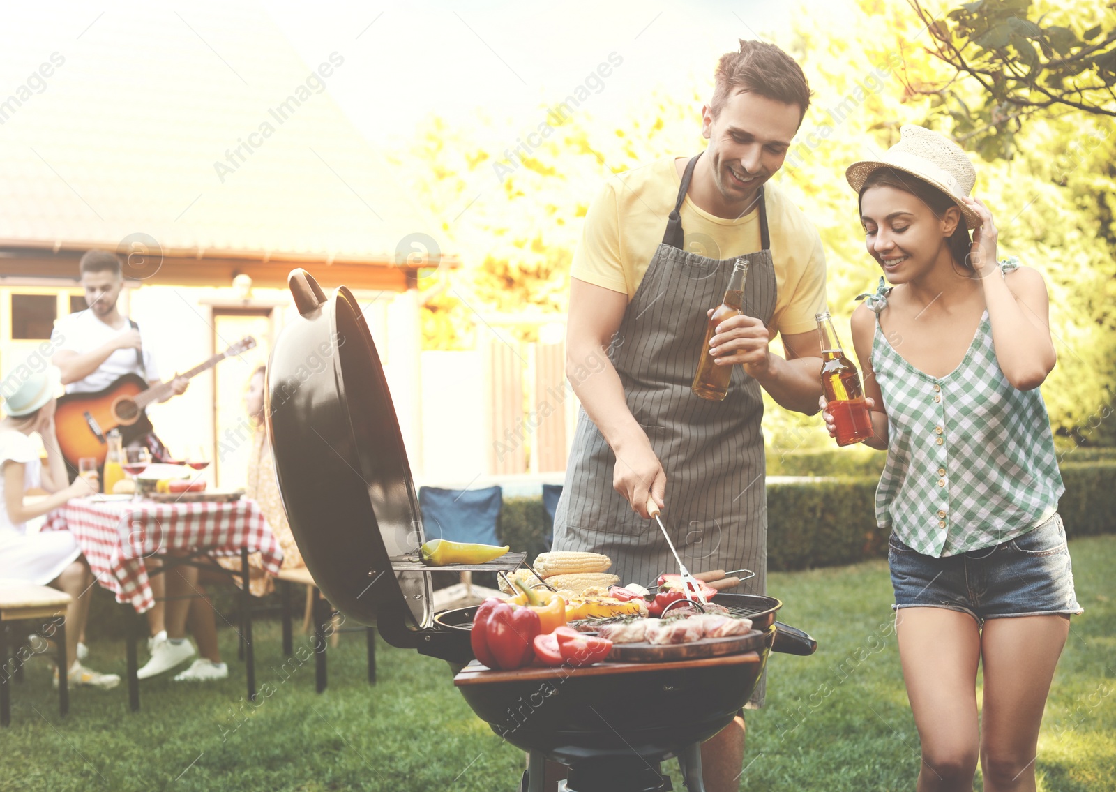 Image of Young man and woman near barbecue grill outdoors on sunny day