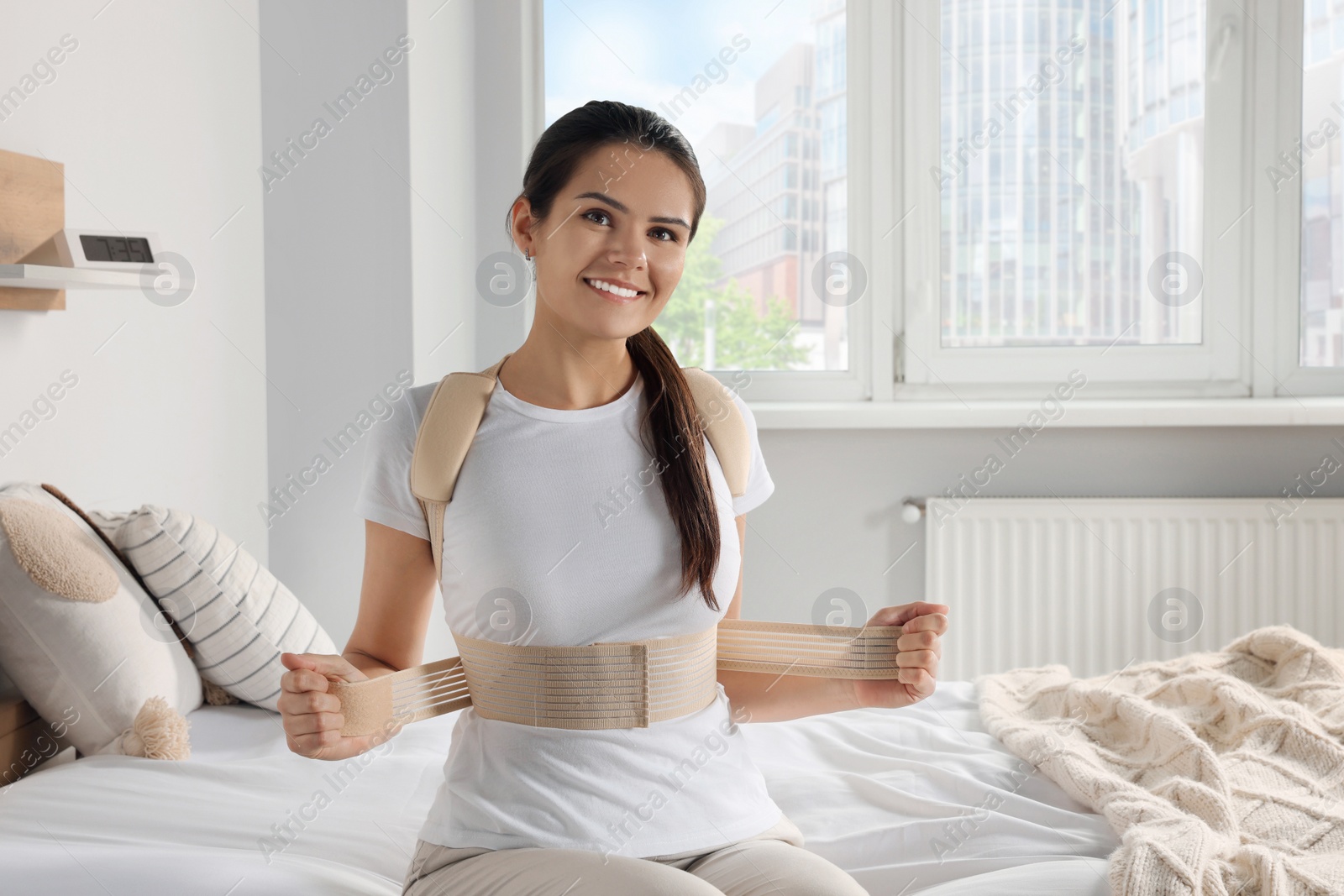 Photo of Woman with orthopedic corset sitting in bedroom