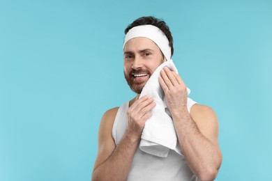 Photo of Washing face. Man with headband and towel on light blue background