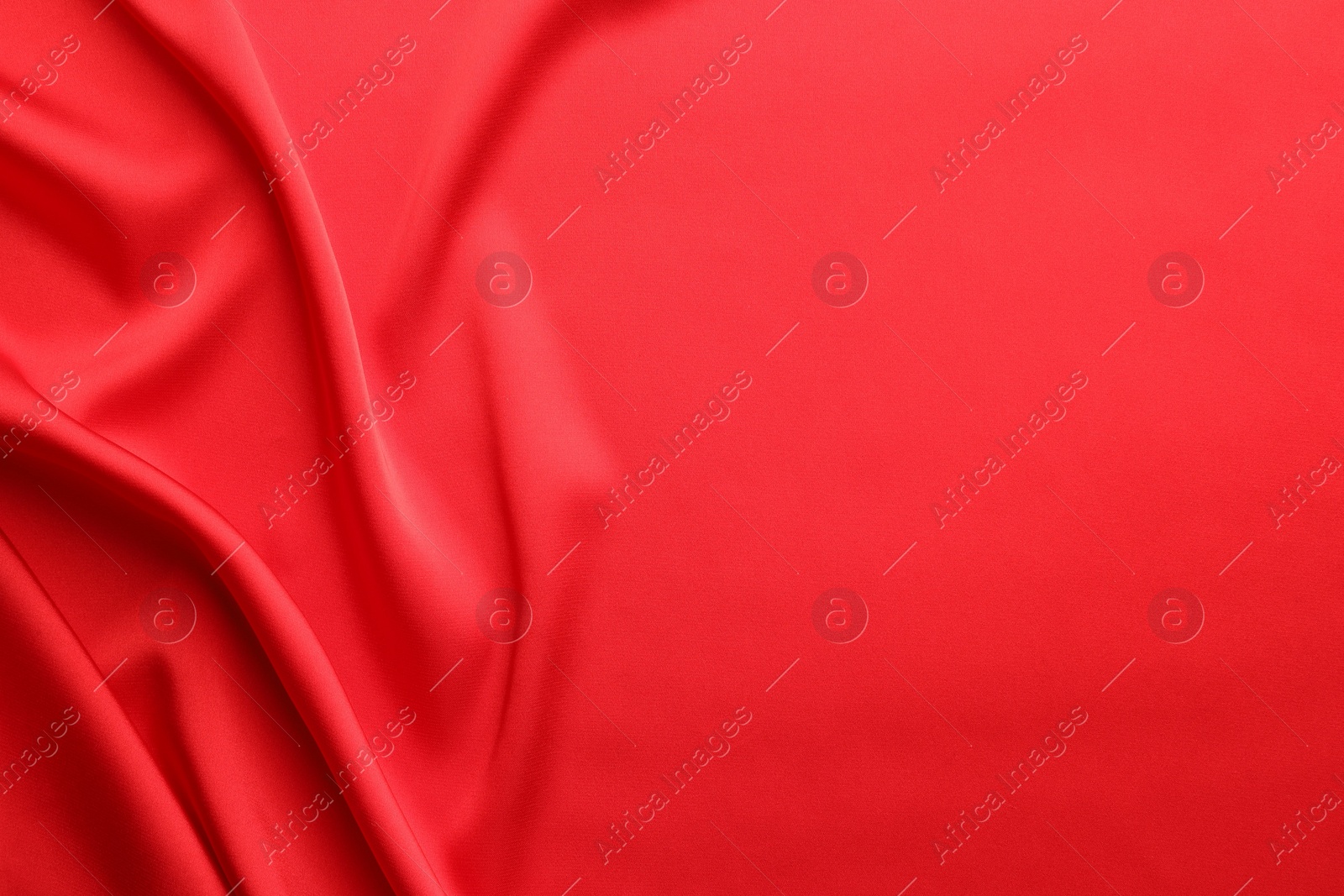 Photo of Crumpled red silk fabric as background, top view. Space for text