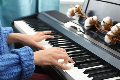 Young woman playing piano at home, closeup