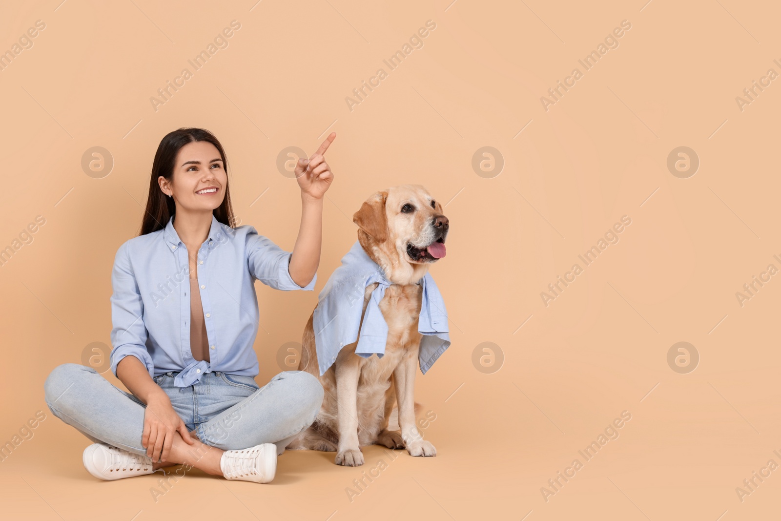 Photo of Happy woman with cute Labrador Retriever on beige background. Space for text