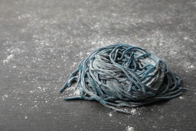 Photo of Rolled spaghetti painted with food coloring and flour on dark grey table, closeup. Space for text