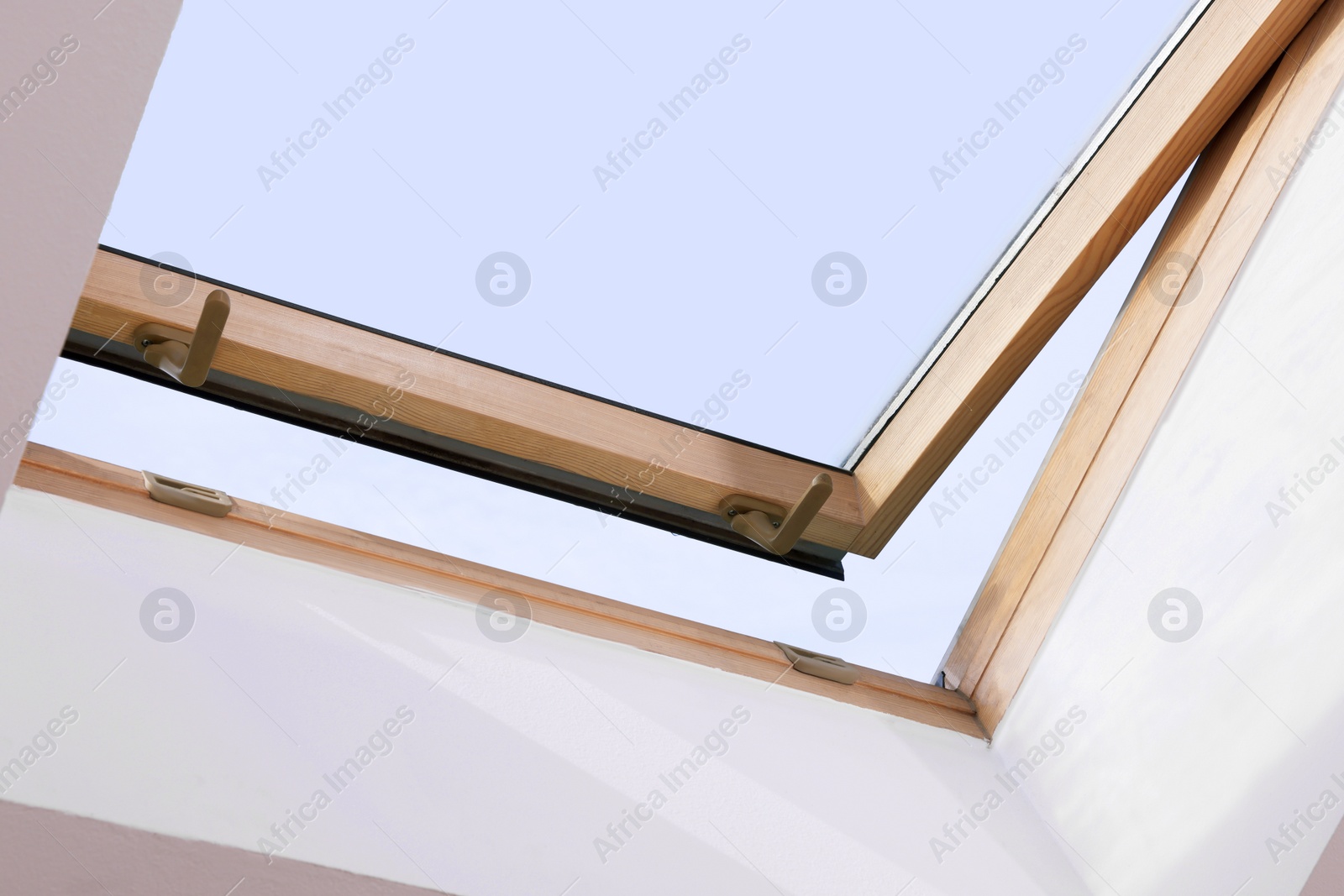 Photo of Open skylight roof window on slanted ceiling in attic room, low angle view