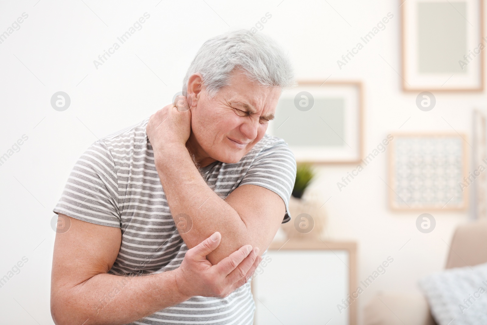 Photo of Mature man suffering from neck pain at home