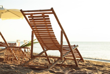Photo of Wooden deck chairs and wicker table with cocktails on sandy beach. Summer vacation