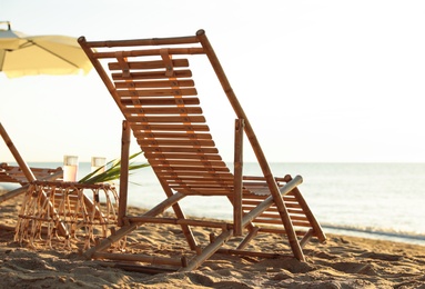 Wooden deck chairs and wicker table with cocktails on sandy beach. Summer vacation