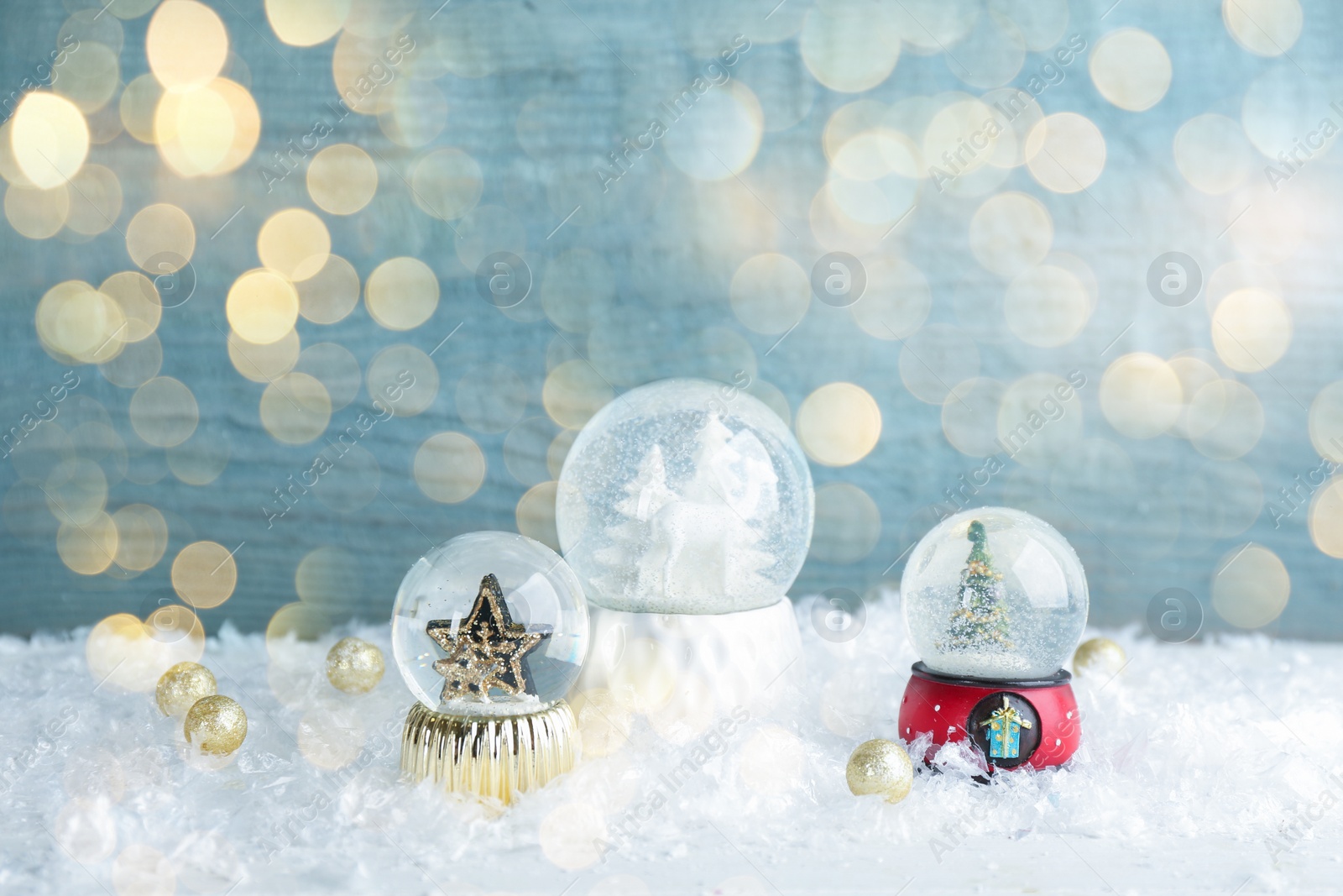 Image of Beautiful Christmas snow globes on light blue background, bokeh effect. Space for text