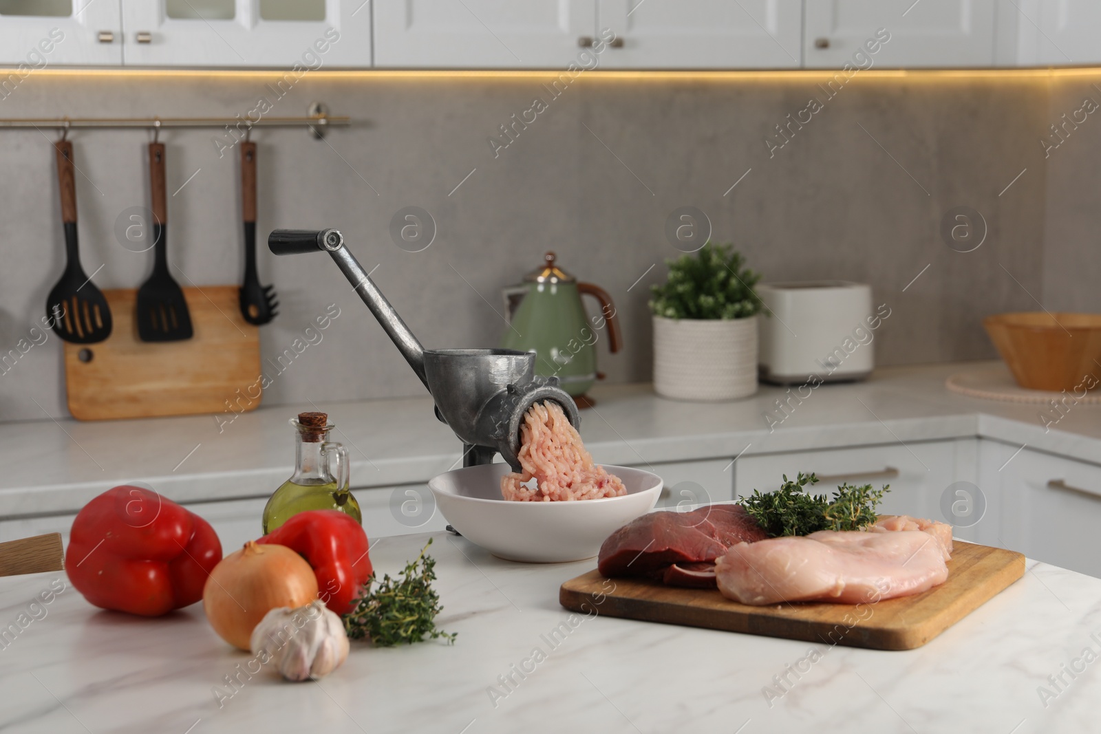 Photo of Metal meat grinder with chicken mince and products on white marble table in kitchen