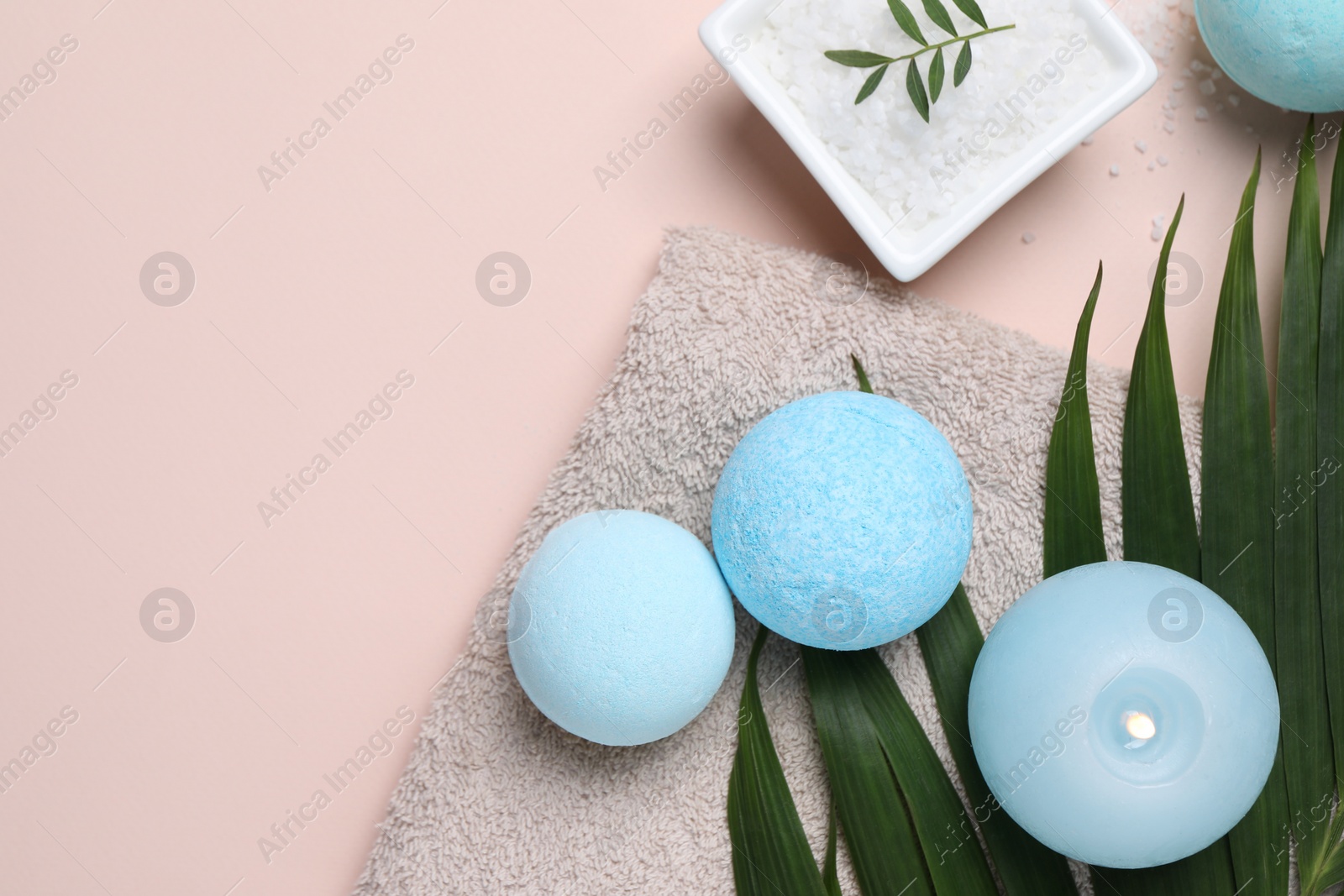 Photo of Bath bombs, green leaf, sea salt and burning candle on beige background, flat lay. Space for text