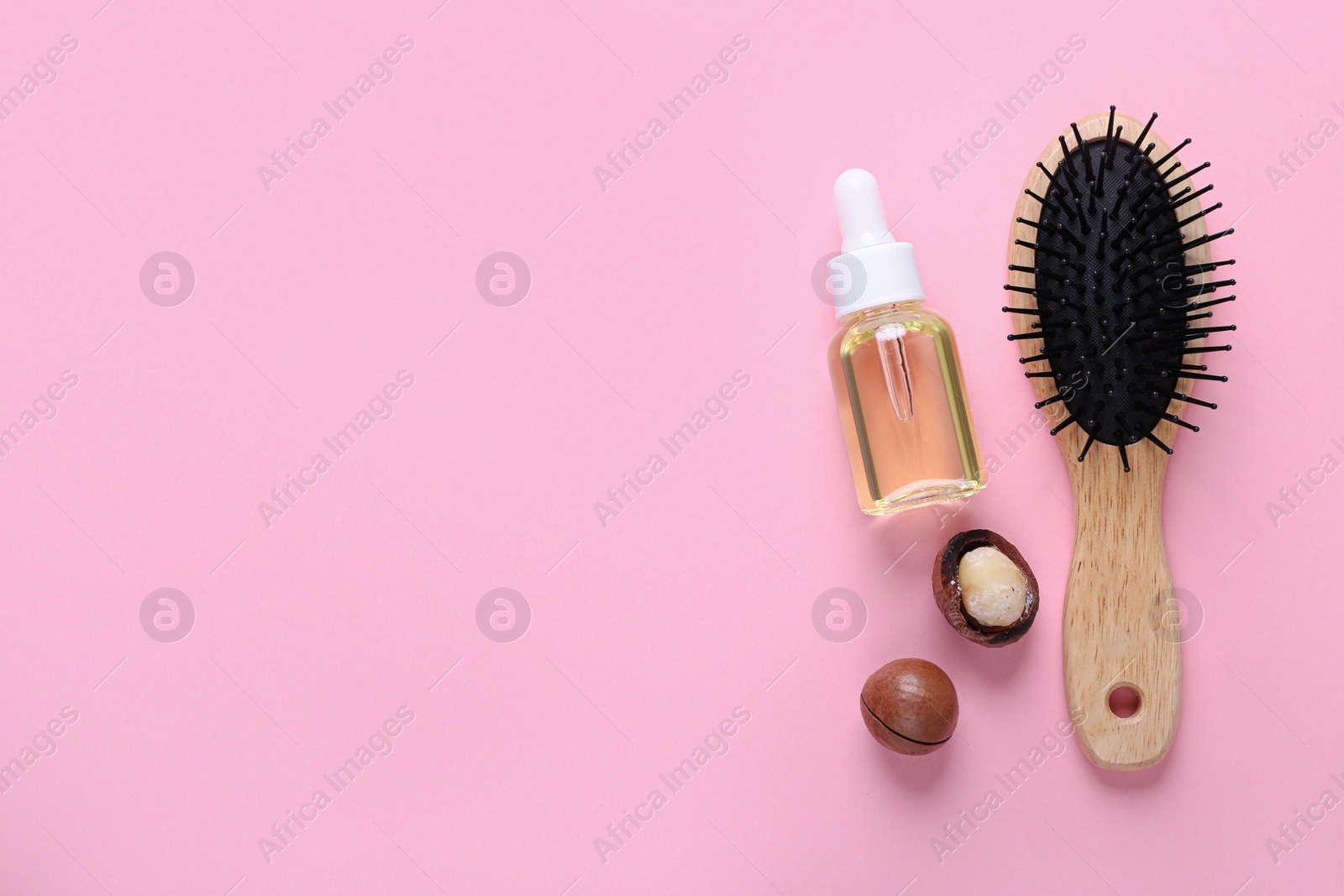 Photo of Delicious organic Macadamia nuts, natural oil and brush on pink background, flat lay. Space for text