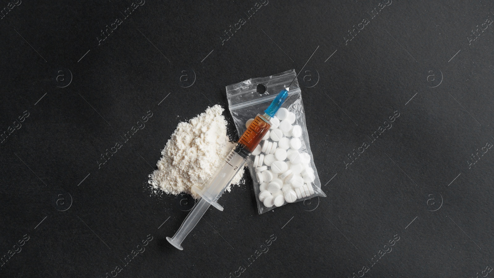 Photo of Powder, syringe and pills on black background, flat lay. Hard drugs
