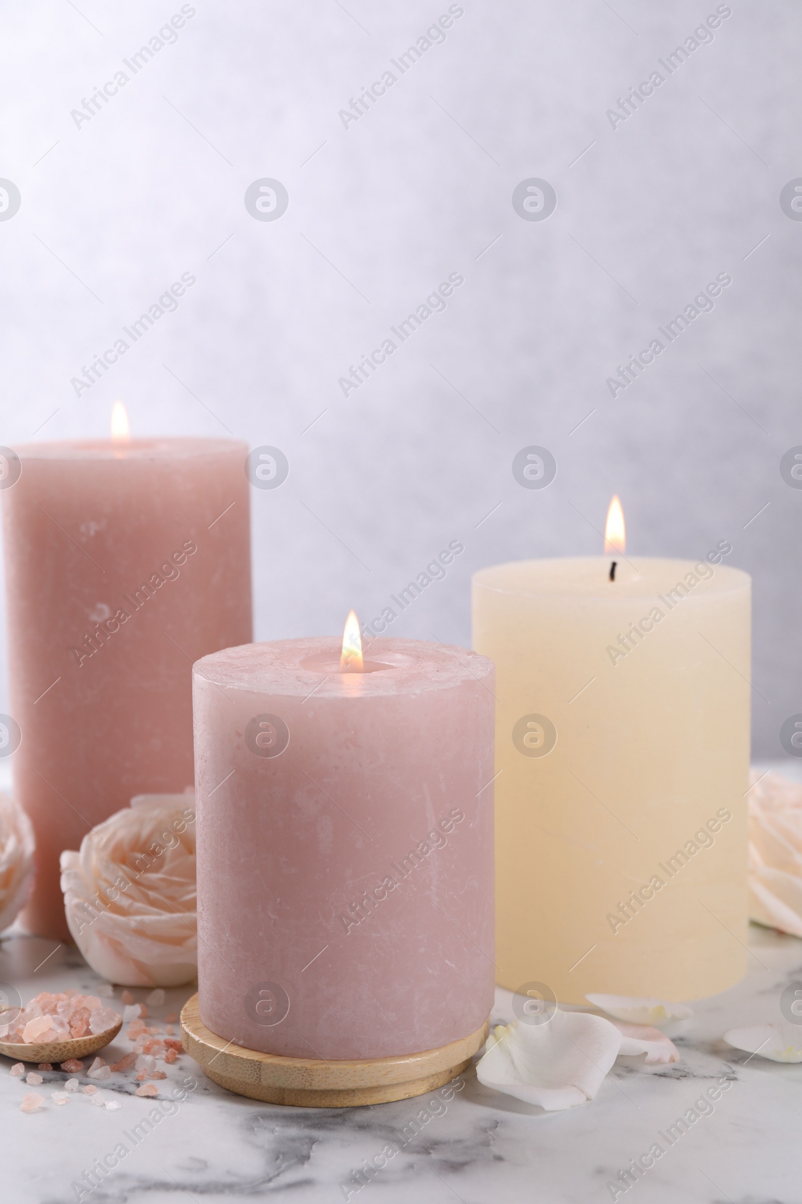Photo of Spa composition with burning candles, flower and sea salt on white marble table
