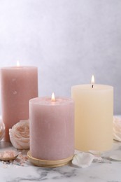 Spa composition with burning candles, flower and sea salt on white marble table