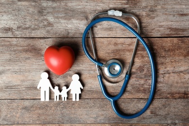 Photo of Flat lay composition with heart, stethoscope and family figure on wooden background. Life insurance concept