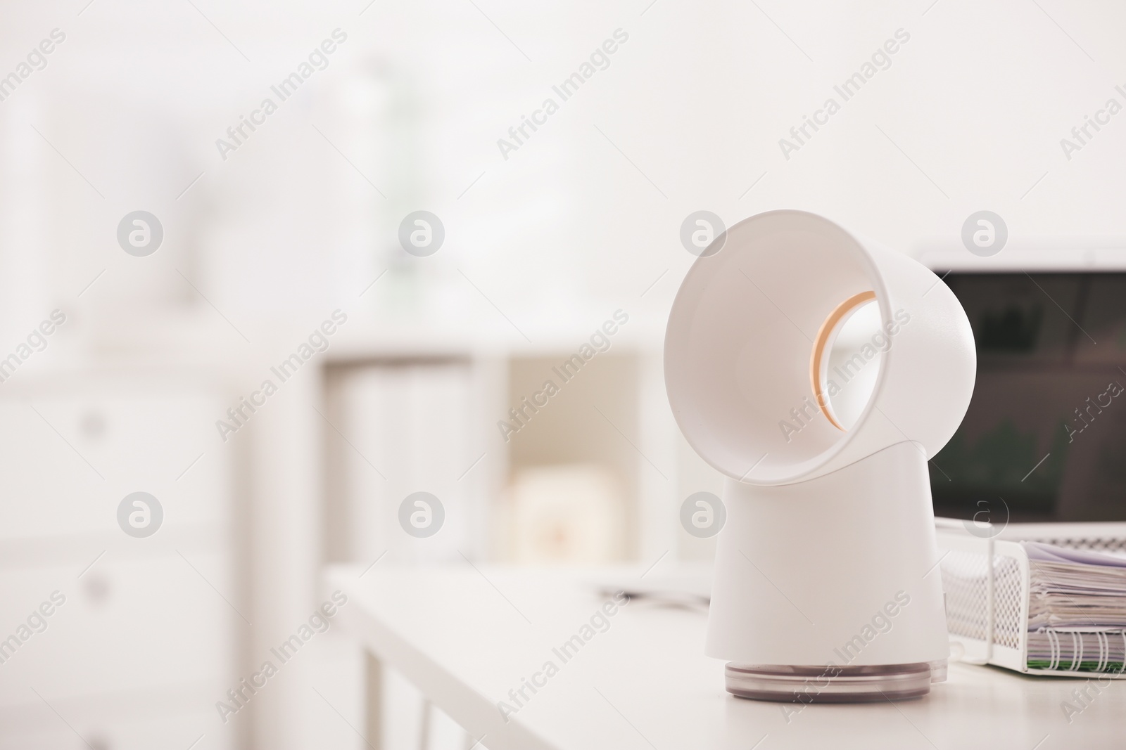 Photo of Modern electric fan on table in office. Space for text