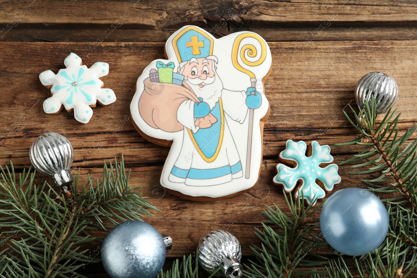 Photo of Tasty gingerbread cookies and festive decor on wooden table, flat lay. St. Nicholas Day celebration