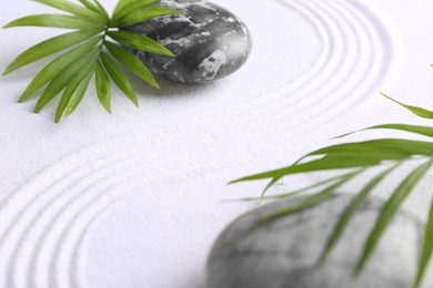 Photo of Zen concept. Stones, leaves and pattern on white sand, closeup. Space for text