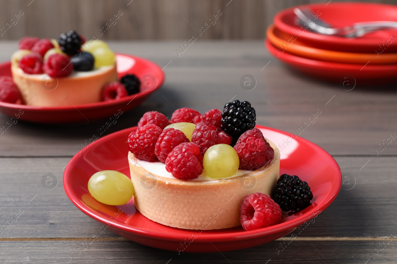 Photo of Delicious tartlets with berries on wooden table