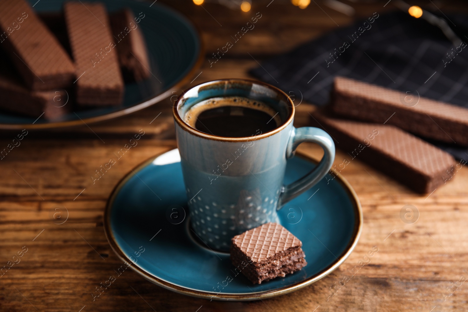 Photo of Delicious wafer and cup of coffee on wooden table