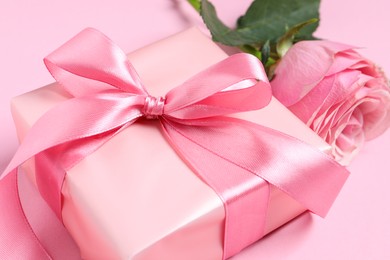 Photo of Gift box and beautiful rose flower on pink background, closeup