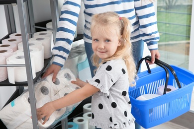 Young mother and little girl choosing toilet paper in shop