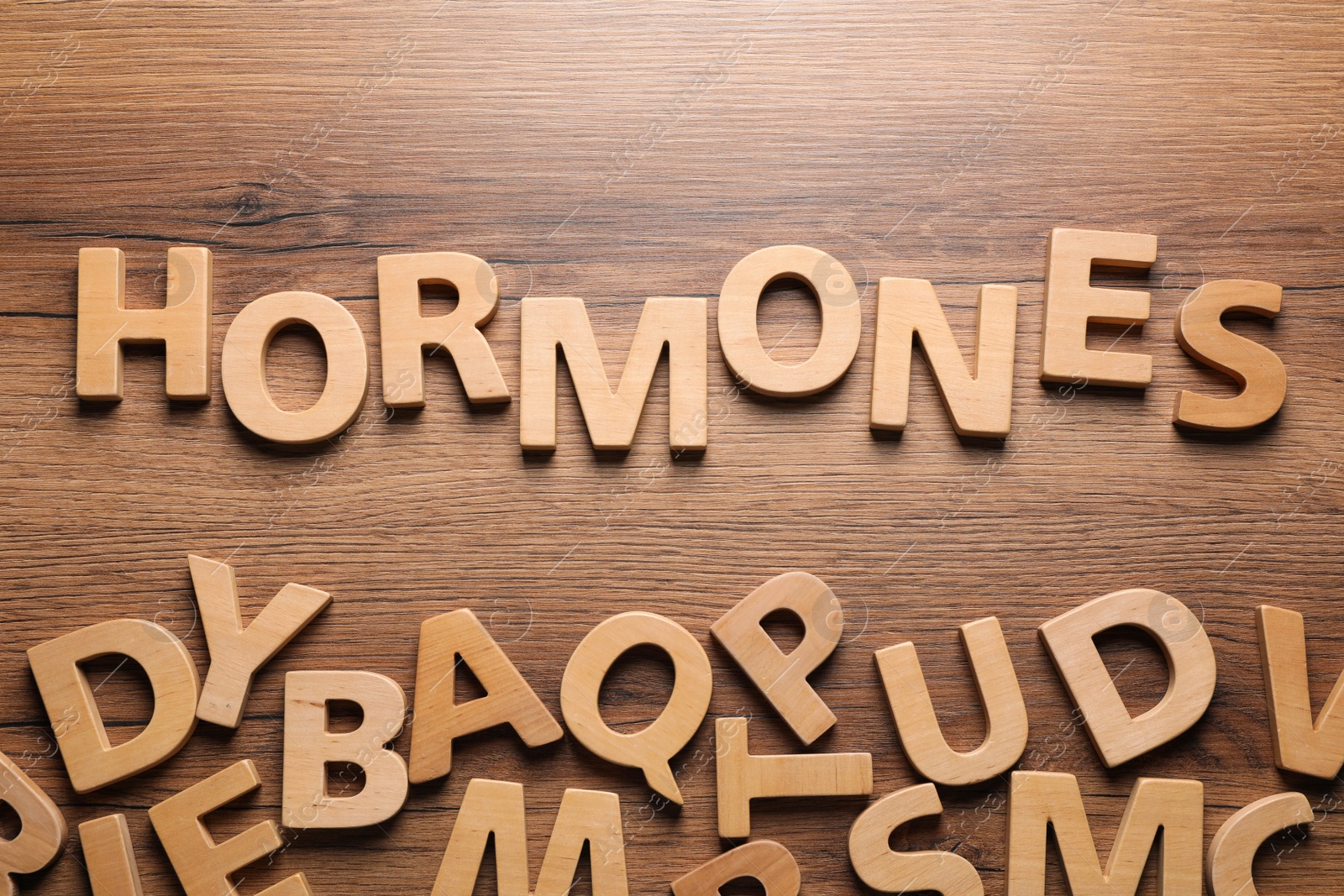 Photo of Word Hormones made of letters on wooden table, flat lay