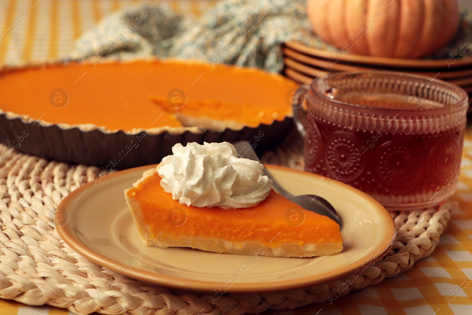 Photo of Piece of fresh homemade pumpkin pie served with whipped cream and tea on table