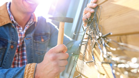 Photo of Man decorating house with Christmas lights outdoors, closeup